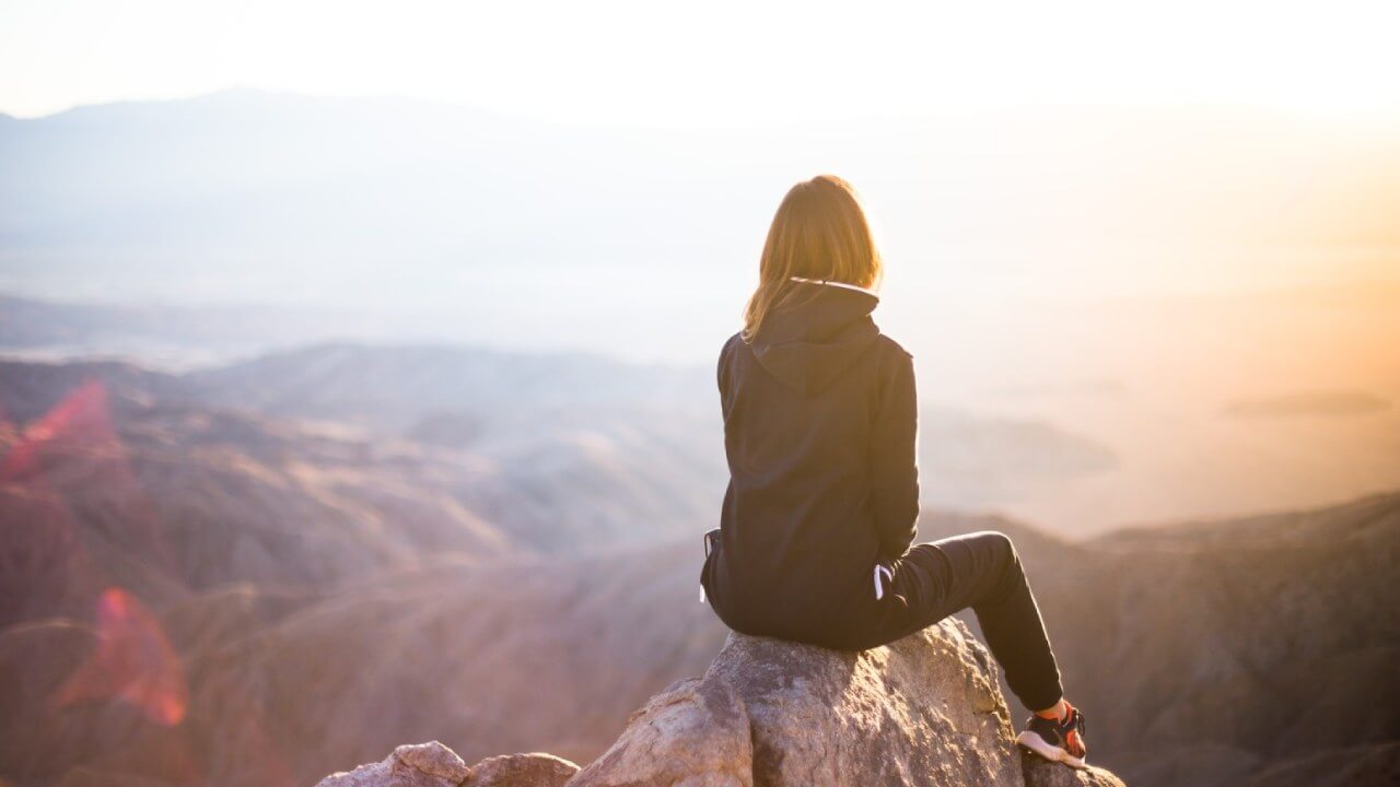 Woman sat on hill top looking out of valley